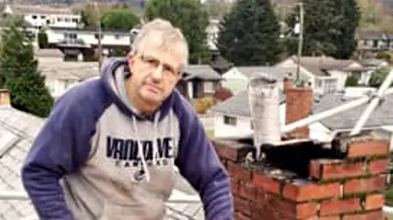 Lindbjerg Chimney technician on a rooftop beside a brick chimney